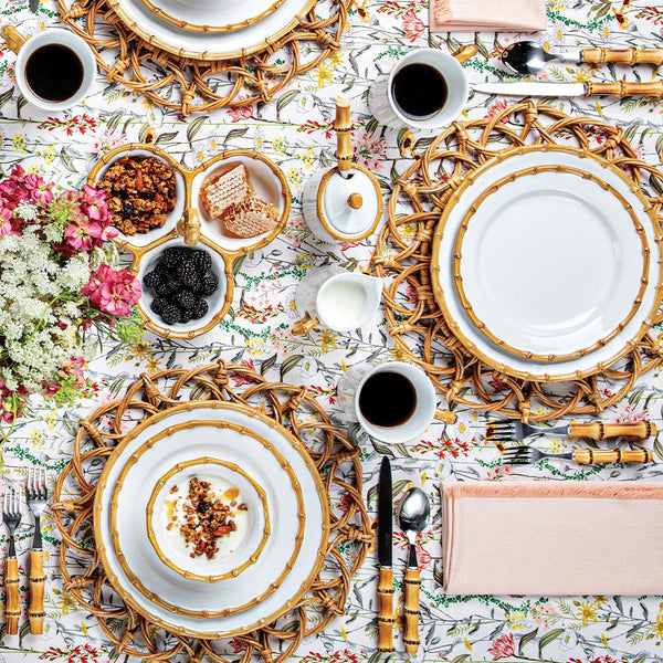 Classic Bamboo natural ceramic charger plate on a floral tablecloth with matching dinnerware.