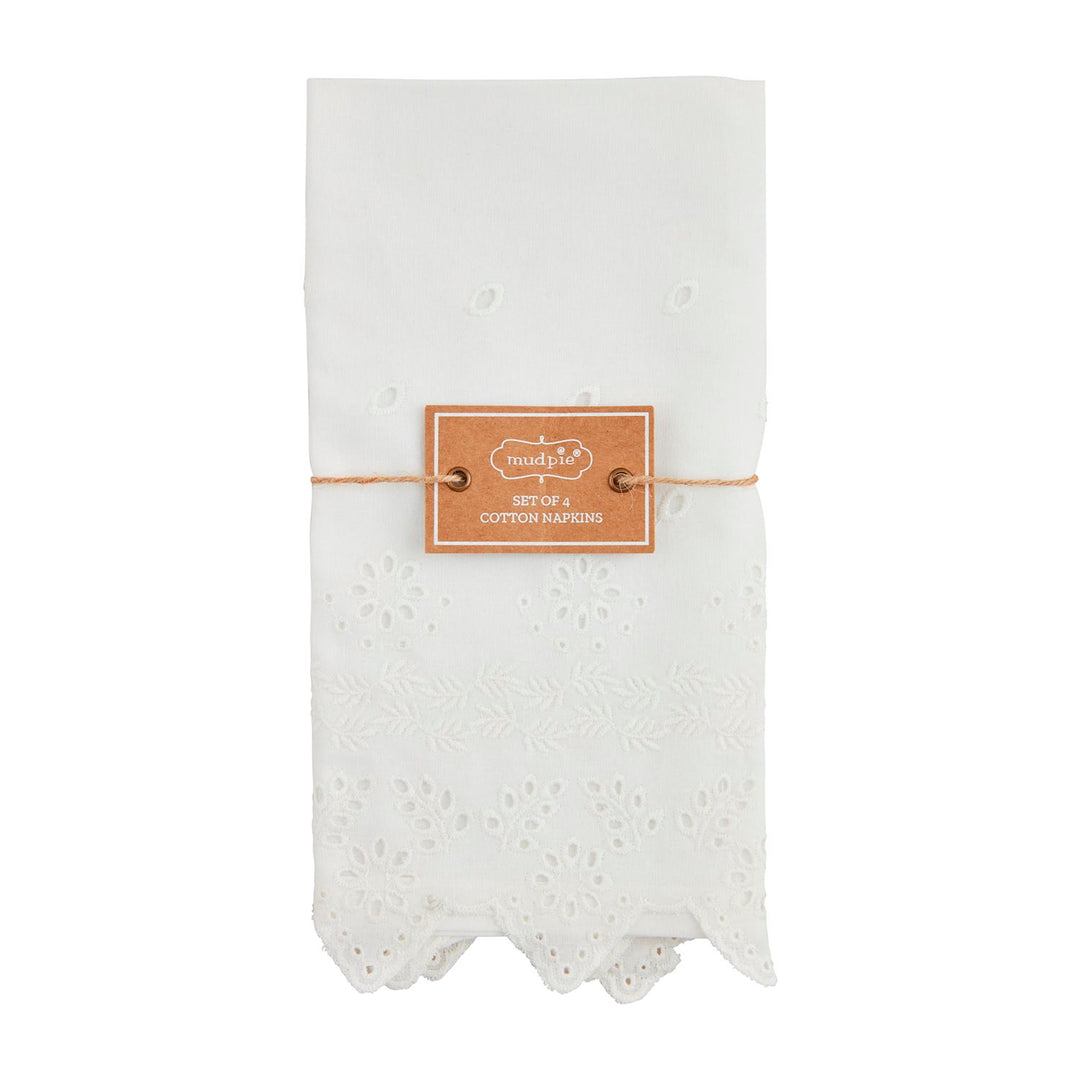 Set of four white cotton napkins with decorative eyelet embroidery and scalloped edges.