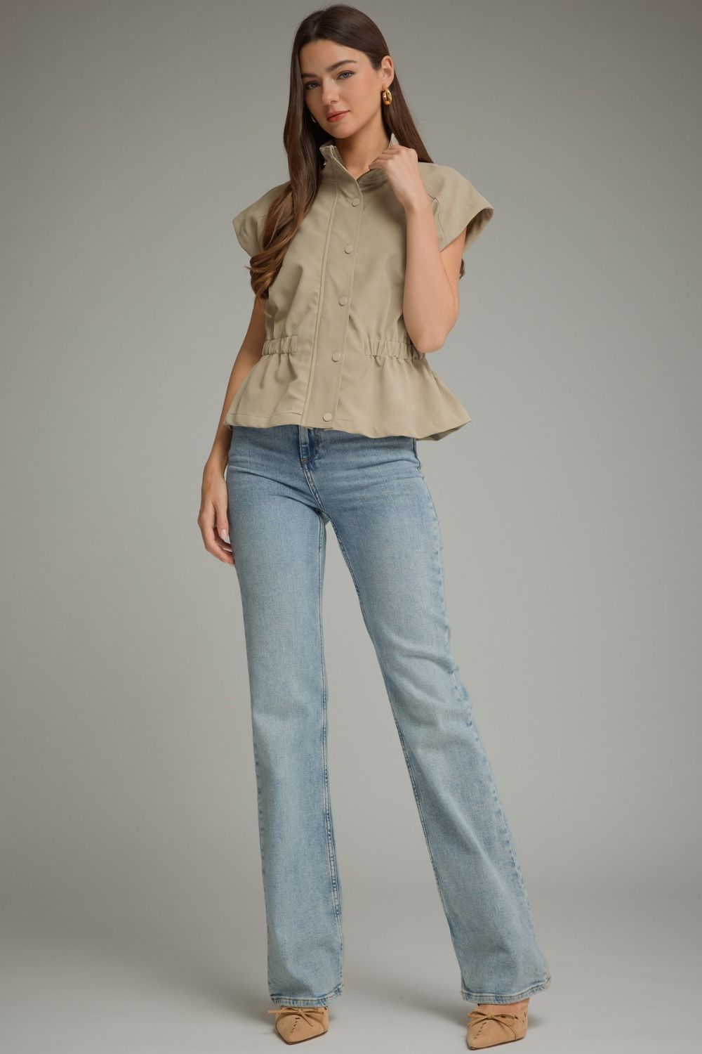 Woman wearing a tan Sarah Solid Cap Sleeve Jacket with light wash denim jeans.