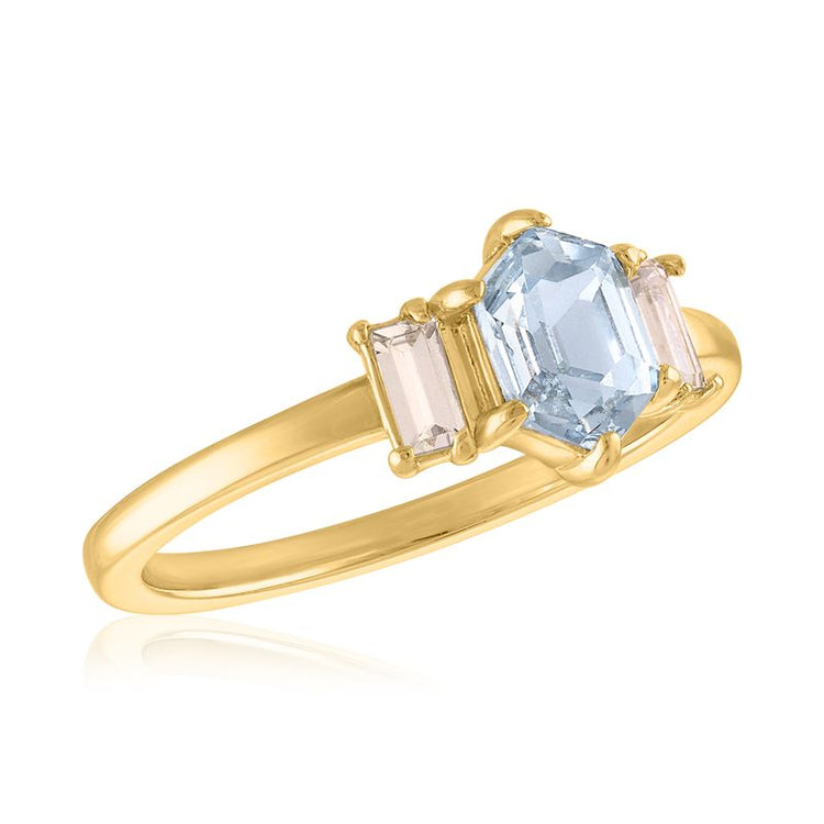 Hexagon step cut light blue center stone ring with baguette side stones on a gold band.