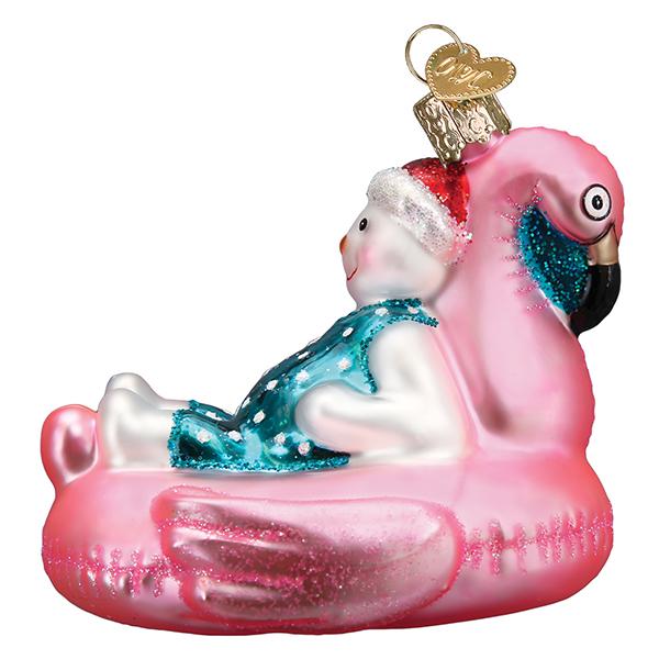 Glass snowman ornament wearing a Santa hat and blue swimsuit, lounging in a pink flamingo pool float.