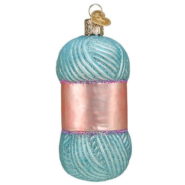 Glass Christmas ornament shaped like a skein of light blue yarn with a pink label and glitter.