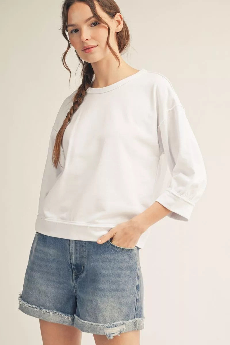 Millie casual top in washed fabric with drop shoulders, raw cut edges, reversed stitching, and a relaxed silhouette.