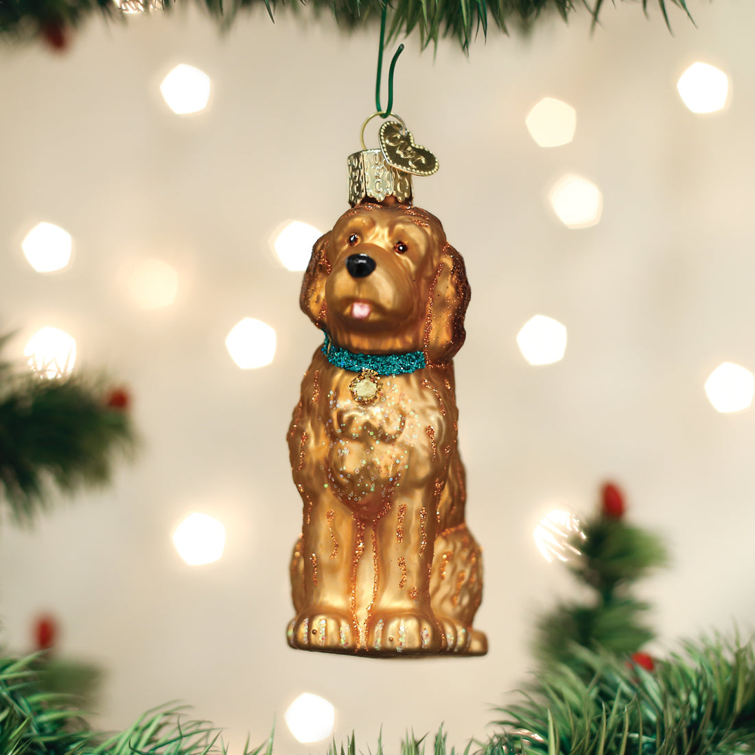 Glass Irish Doodle dog ornament with a golden coat and teal collar hanging on a Christmas tree.