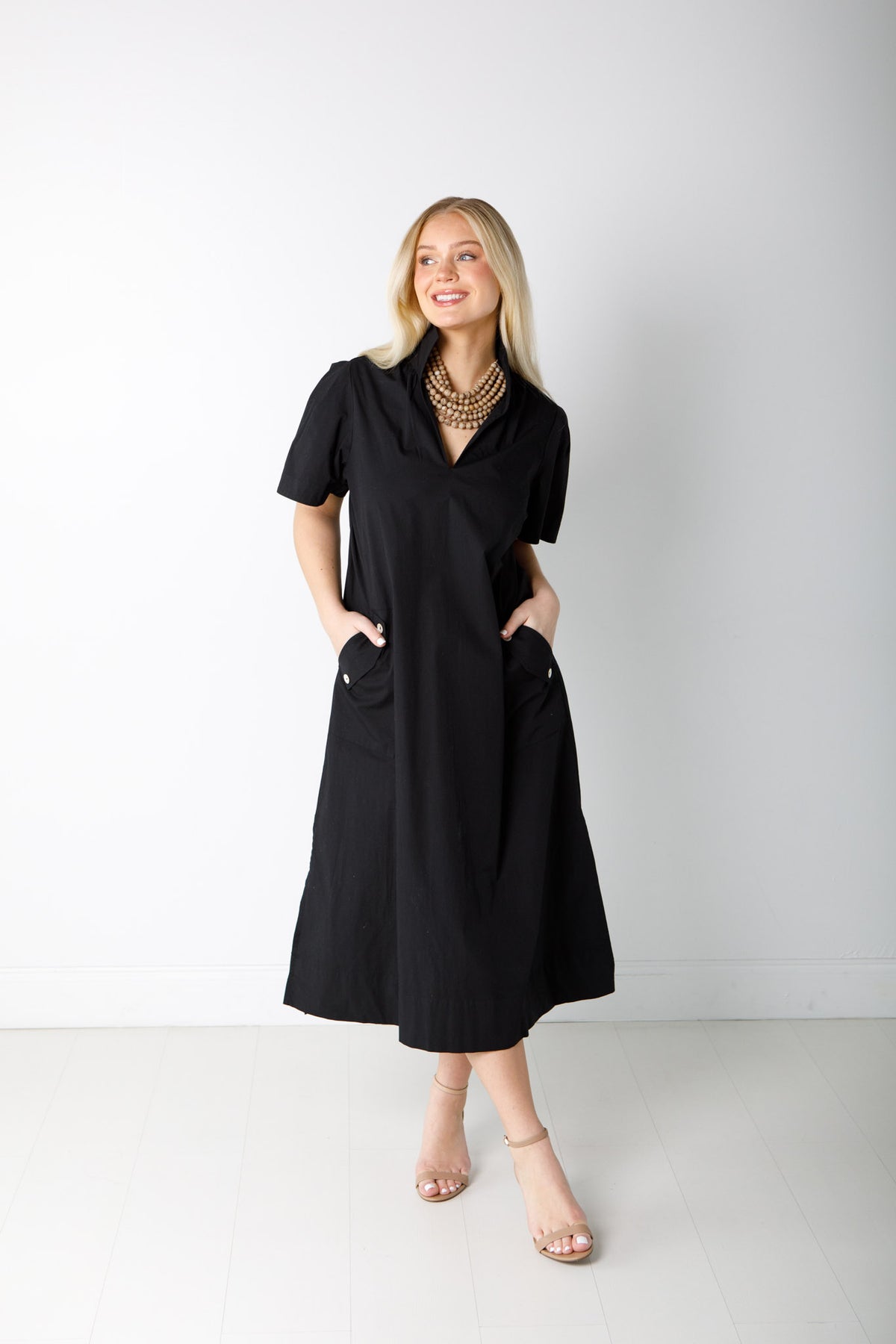 Woman wearing the black Gretchen Dress with a stand collar, short sleeves, and front button pockets.