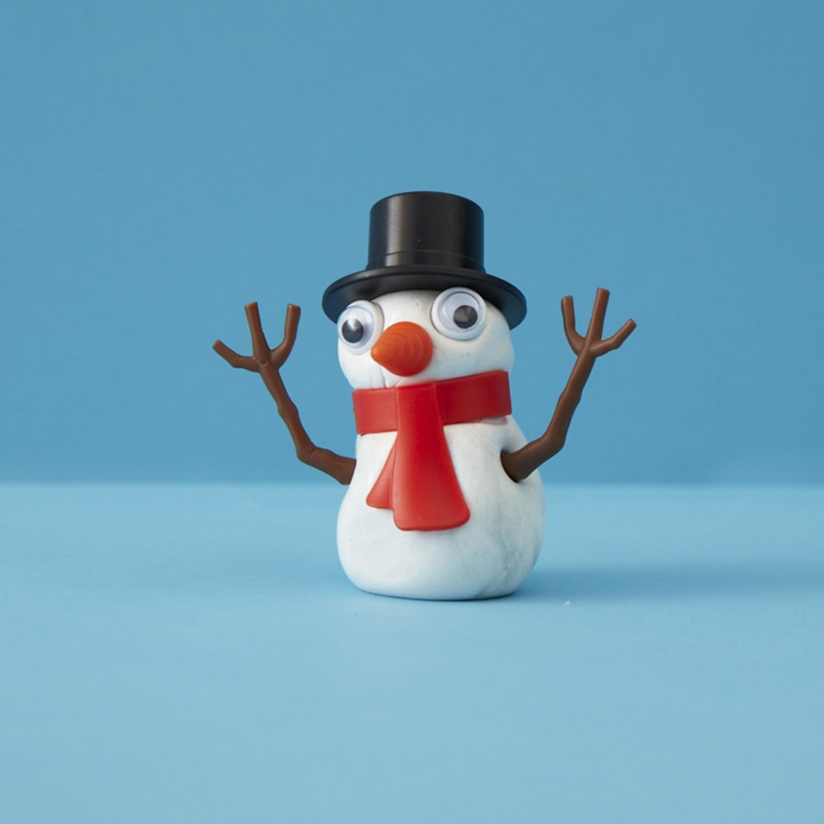 Miracle Melting Snowman with a black top hat, red scarf, googly eyes, and stick arms.