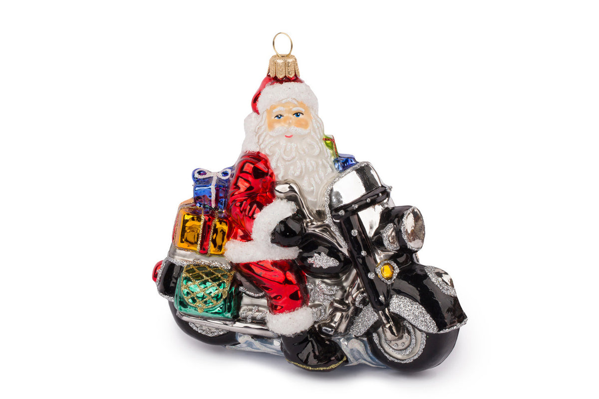 Glass Christmas ornament of Santa Claus riding a black motorcycle with a stack of colorful gifts.