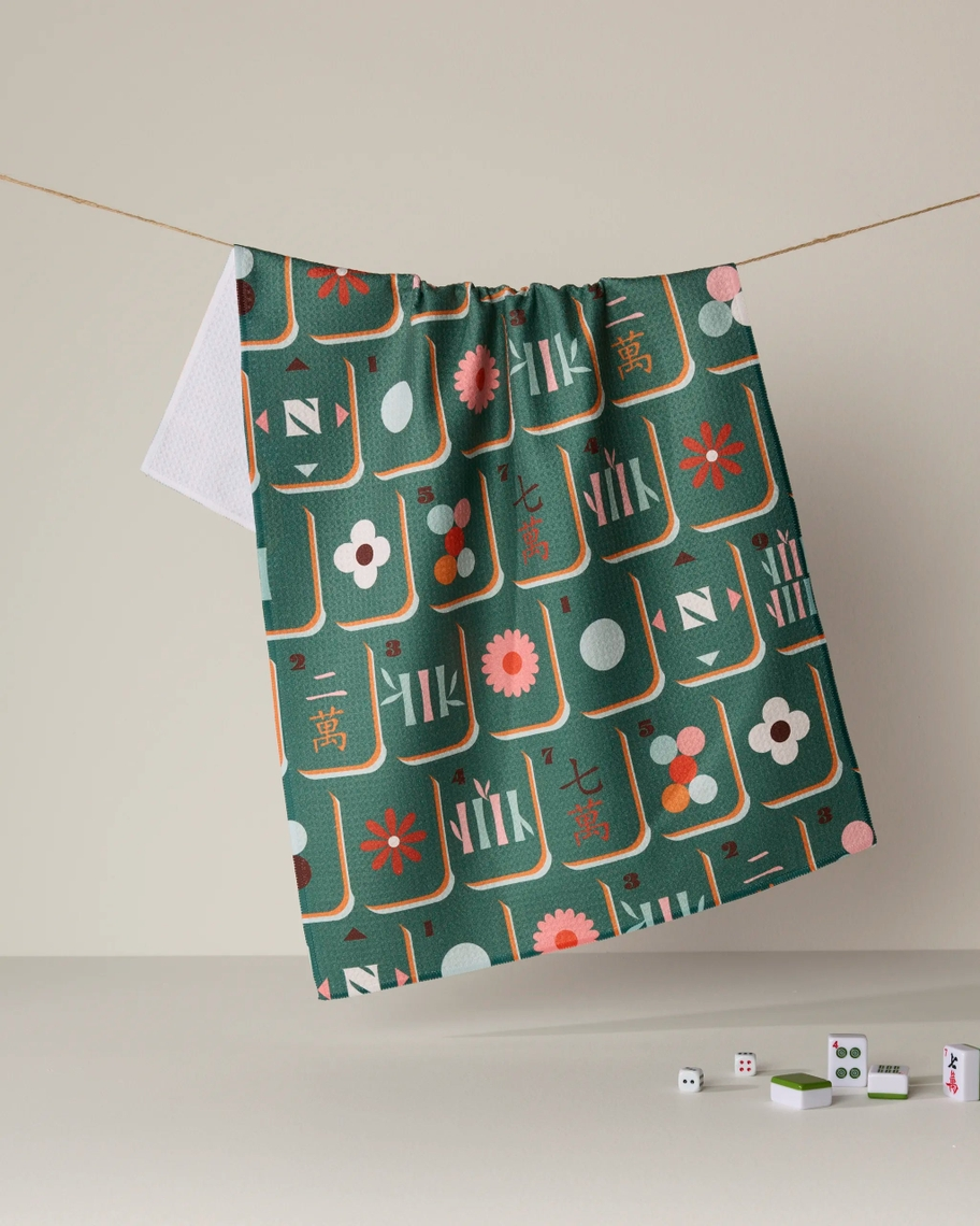 Green Everyday Tea Towel with a colorful mahjong tile pattern hanging on a clothesline.