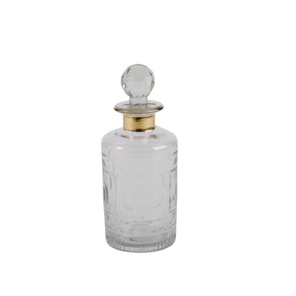 Glass decanter with gold rim trim on a neutral background
