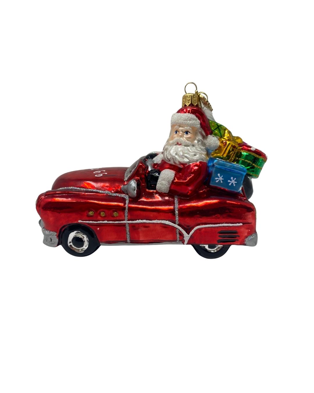 Glass Christmas ornament of Santa Claus driving a red vintage Oldsmobile filled with gifts.