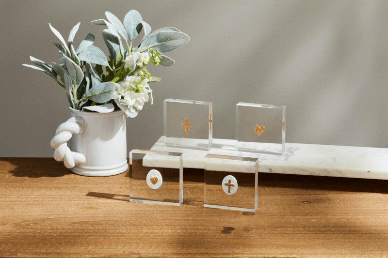 Four 3x3 inch mini acrylic sitters with hand-painted gold cross and heart icons on a wooden table.