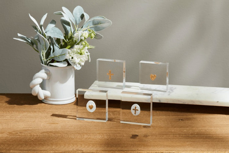 Four 3x3 inch mini acrylic sitters with hand-painted gold cross and heart icons on a wooden table.