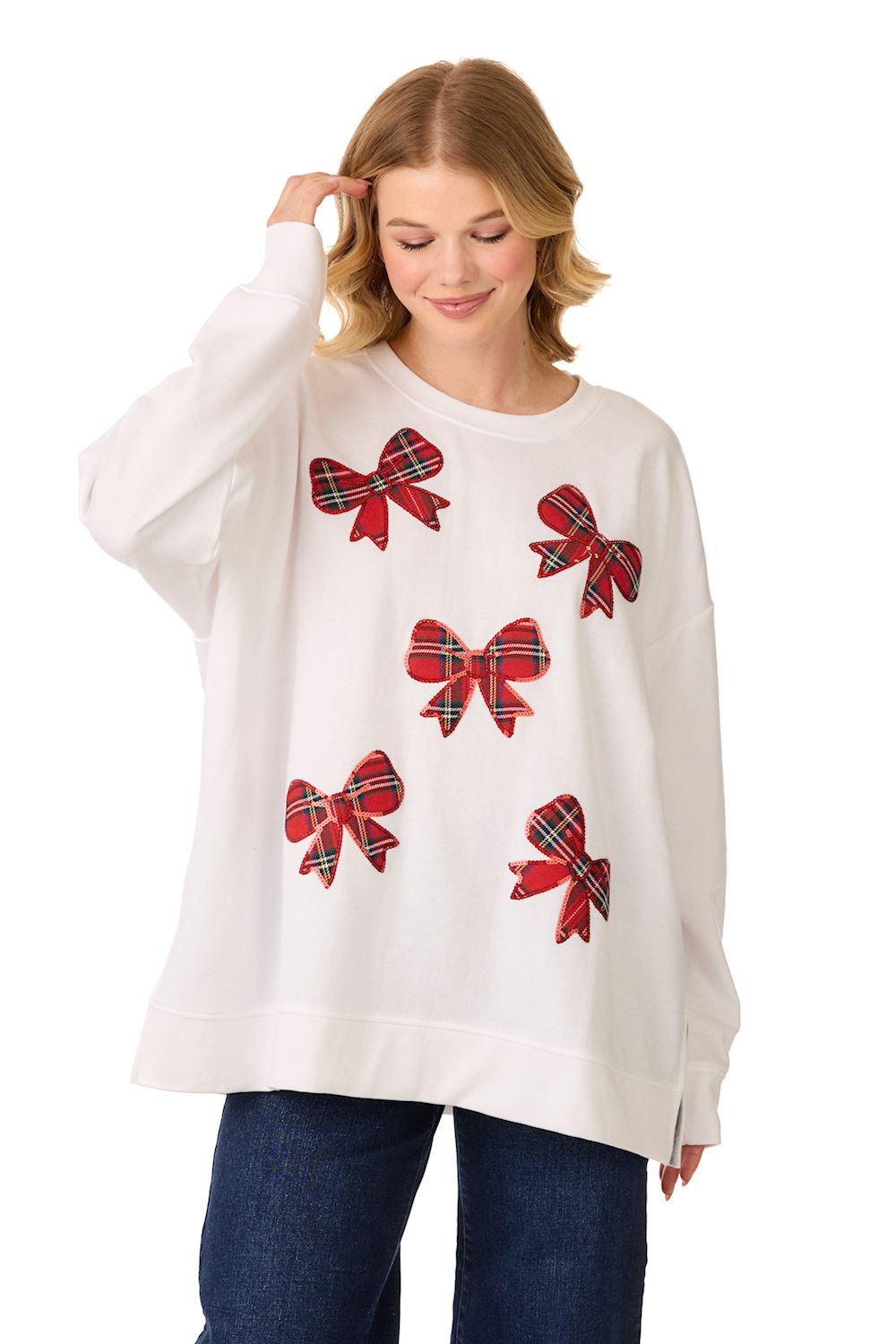 Woman wearing a white oversized sweatshirt featuring five red tartan plaid bow appliqués.
