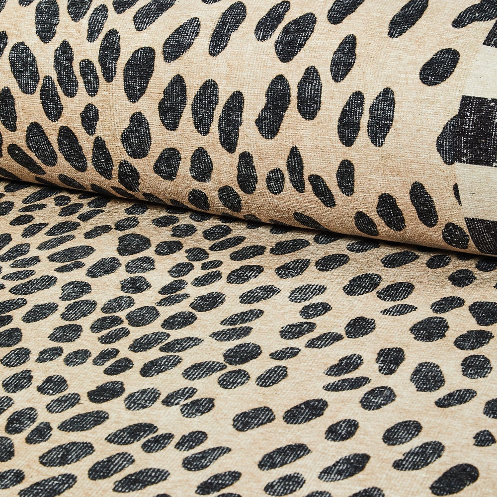Close-up of a Snow Leopard washable rug featuring black spots on a beige background.