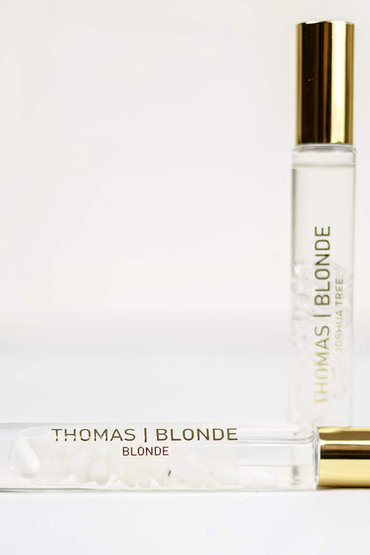 Two High-Roller perfume sticks with gold caps, one standing and one lying down with white crystals.