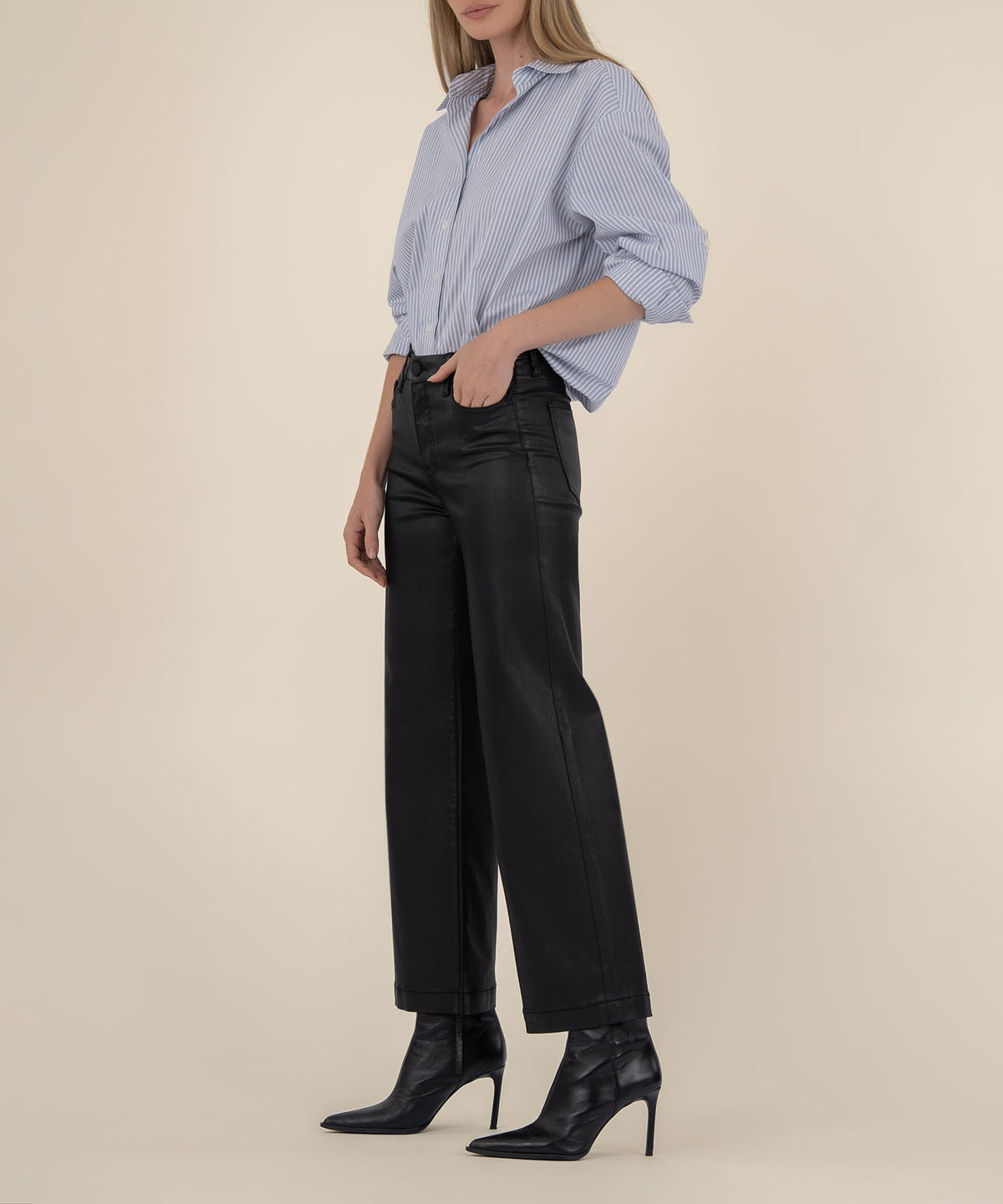 Woman wearing black high-rise wide-leg pants with a wide hem and a blue striped button-down shirt.