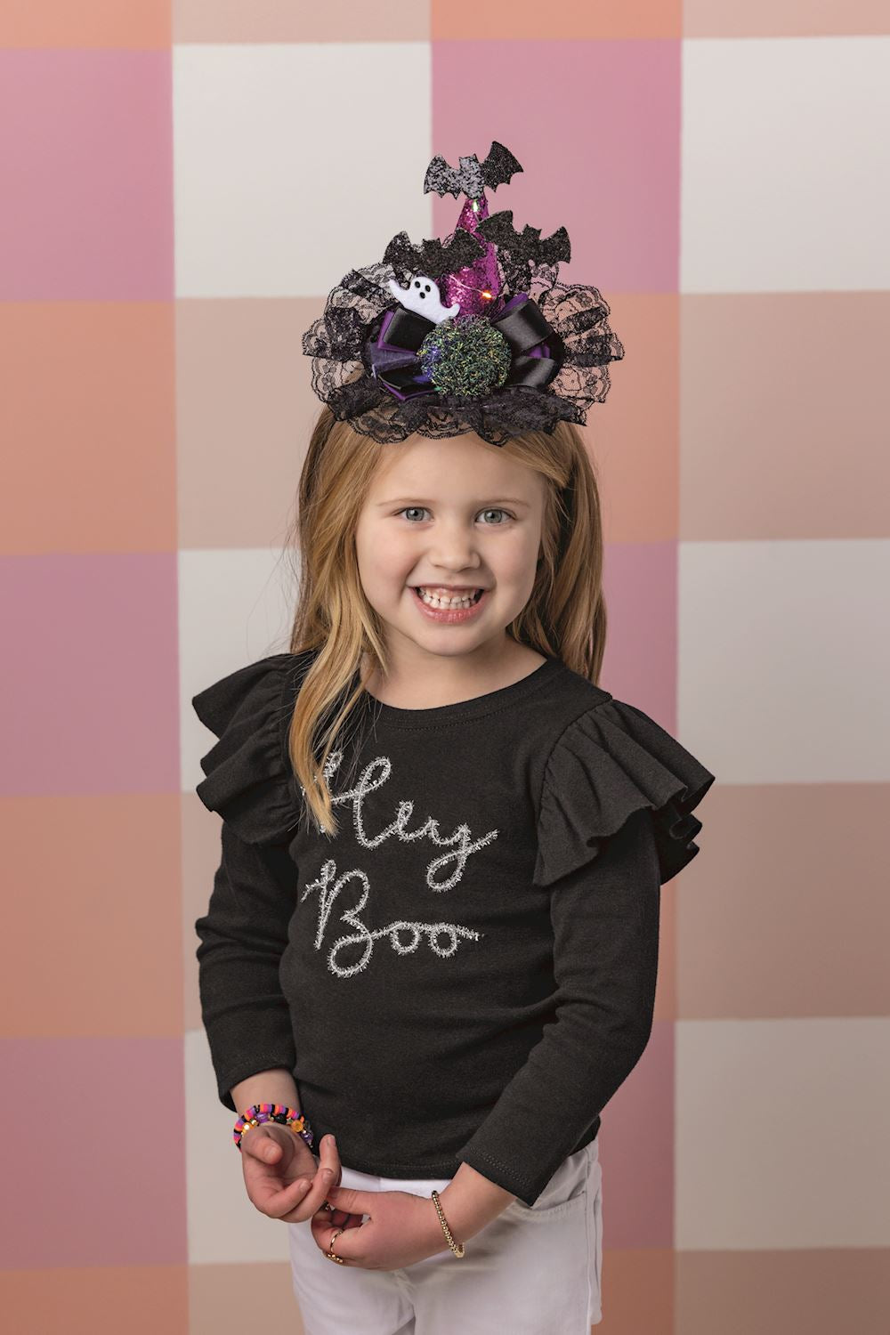 Young girl wearing a Halloween light-up headband with a purple glitter hat, bats, and black lace.