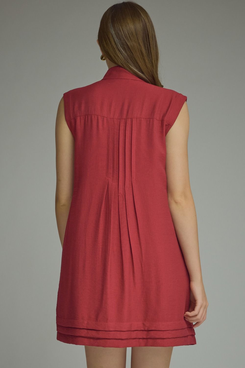 Back view of a woman wearing the red sleeveless Thea D31604 mini dress with pleated back detail.
