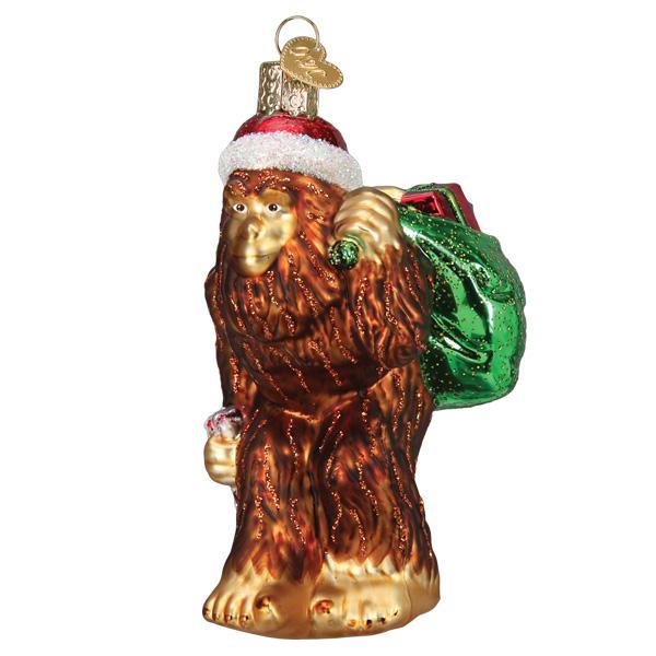 Santa Sasquatch glass ornament wearing a red hat and carrying a green sack of gifts.