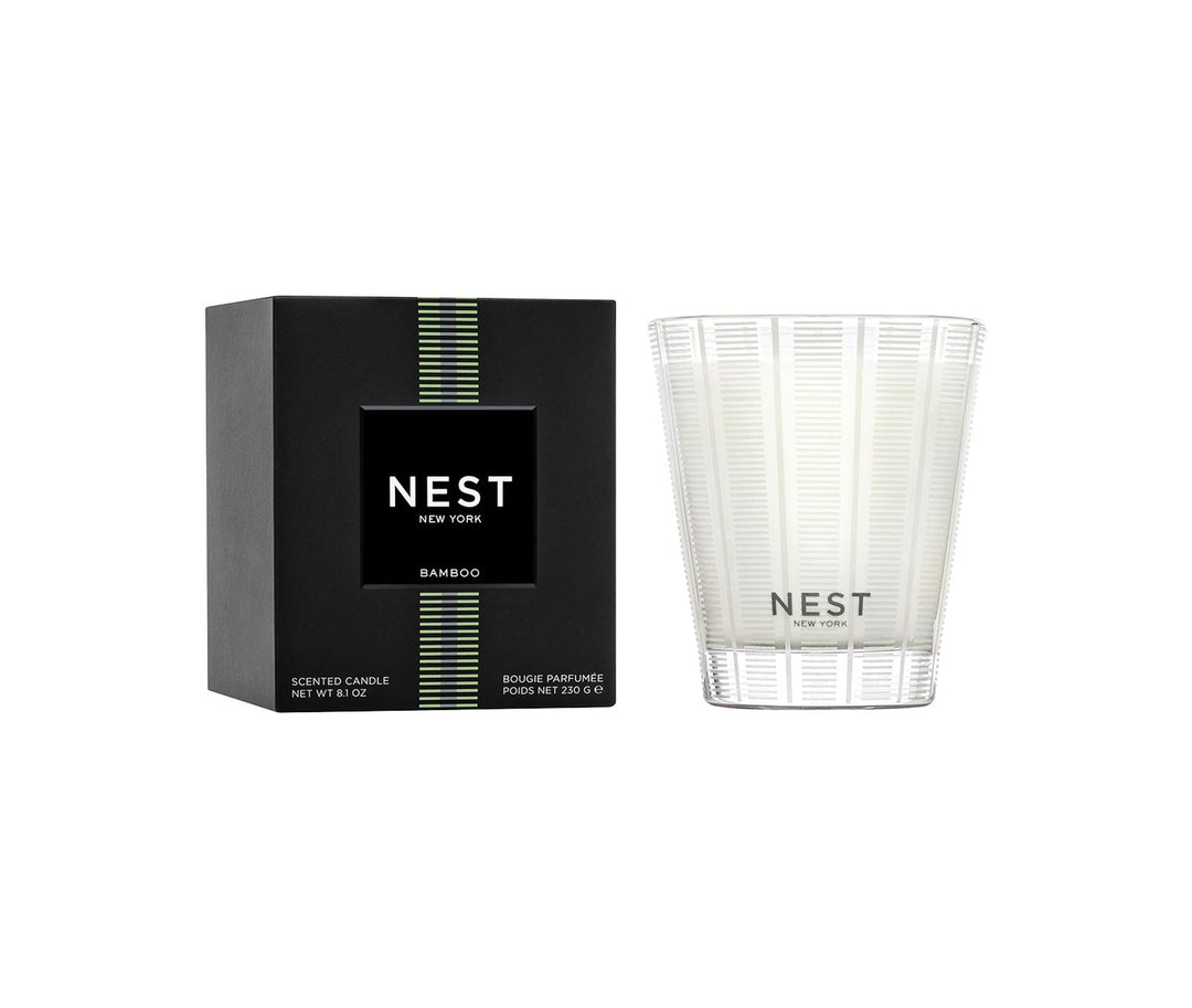 Nest Bamboo scented candle in a frosted glass vessel next to its black and green box.