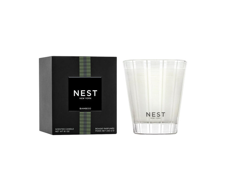 Nest Bamboo scented candle in a frosted glass vessel next to its black and green box.