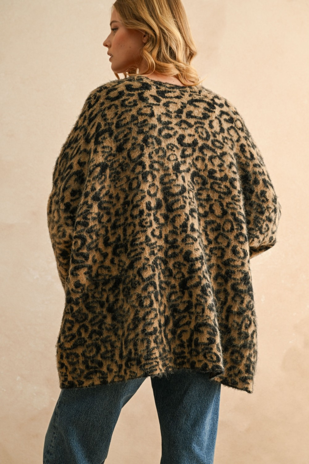 Back view of a woman wearing the Courtney Leopard Oversized Cardigan in a fuzzy knit with blue jeans.