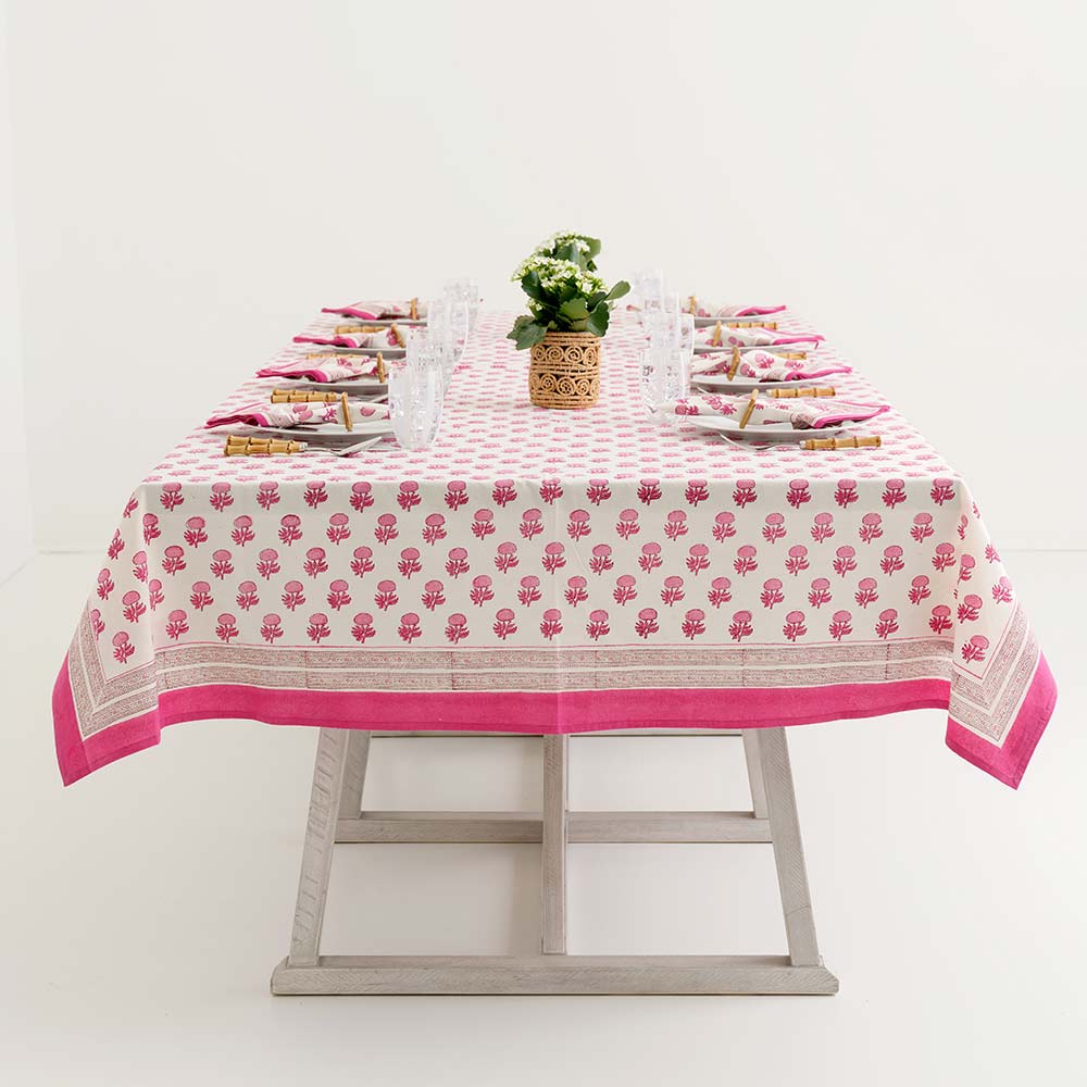 Rosé Tablecloth with pink floral block print on a set dining table with white plates and glasses.