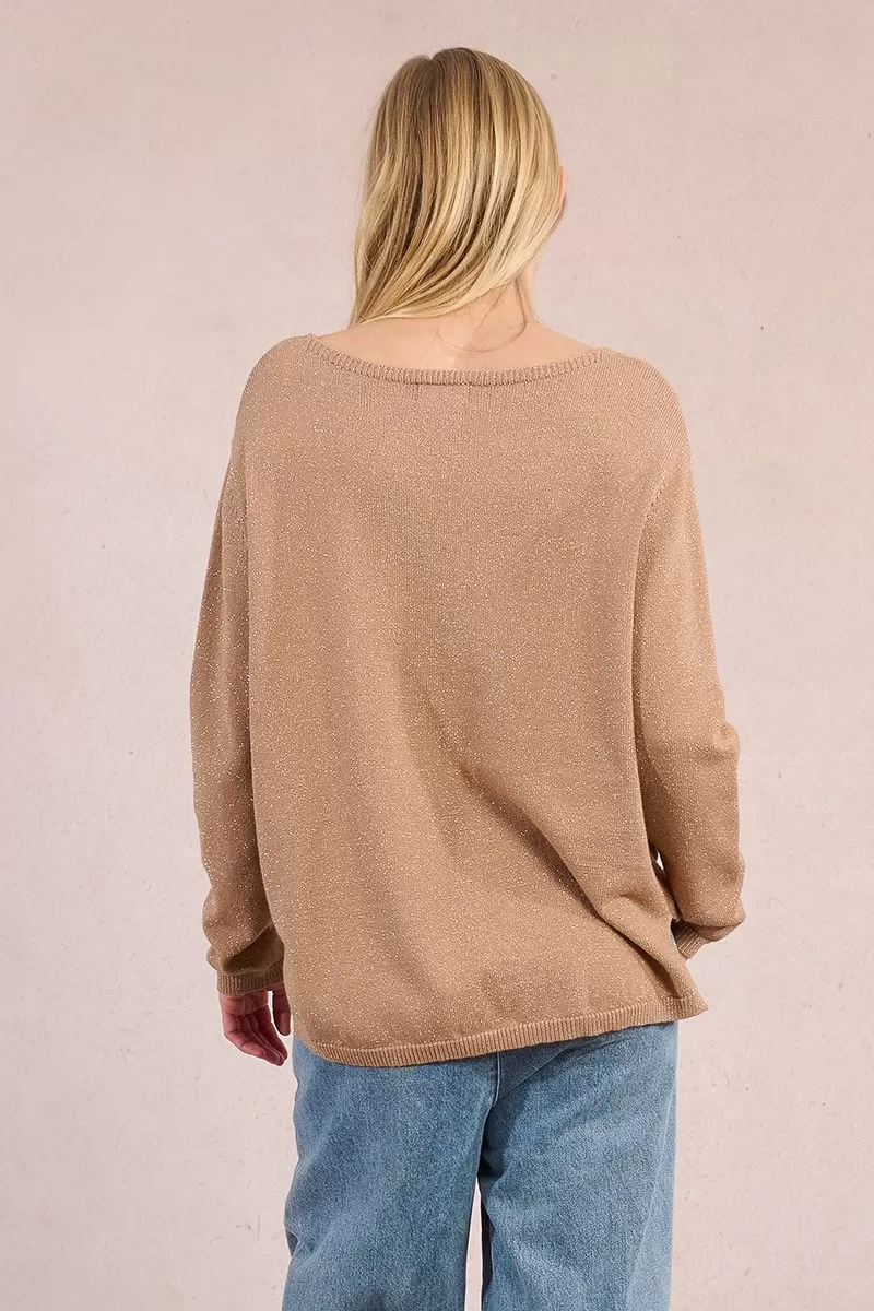 Back view of a woman wearing the Lesli tan knitted sweater with a subtle shimmer and blue jeans.