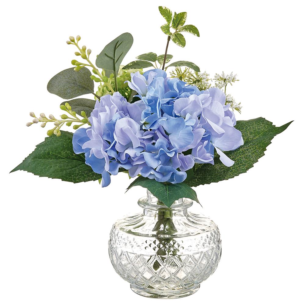 Glass vase holding artificial hydrangea flowers with green foliage.