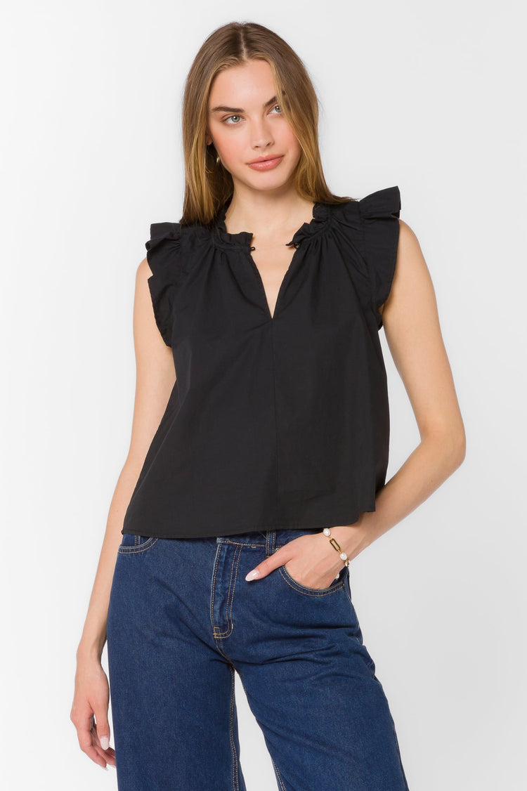 Woman wearing the Nazira Top, a black sleeveless cotton poplin top with a ruffled mandarin collar.