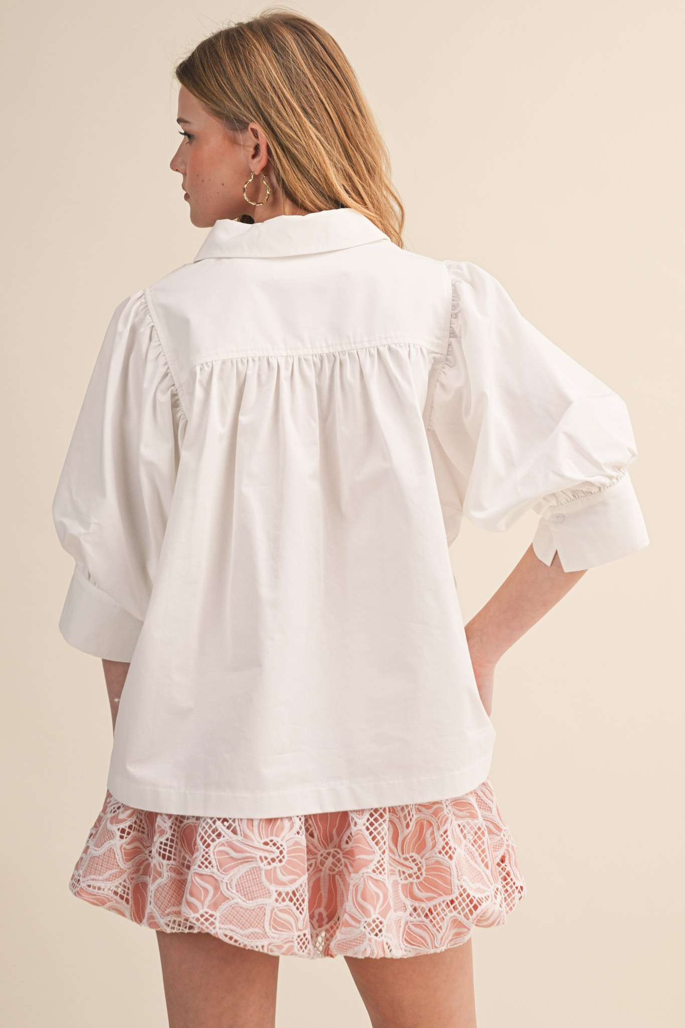 Back view of a woman wearing a white Krisha puff sleeve button down top with a pleated back yoke.