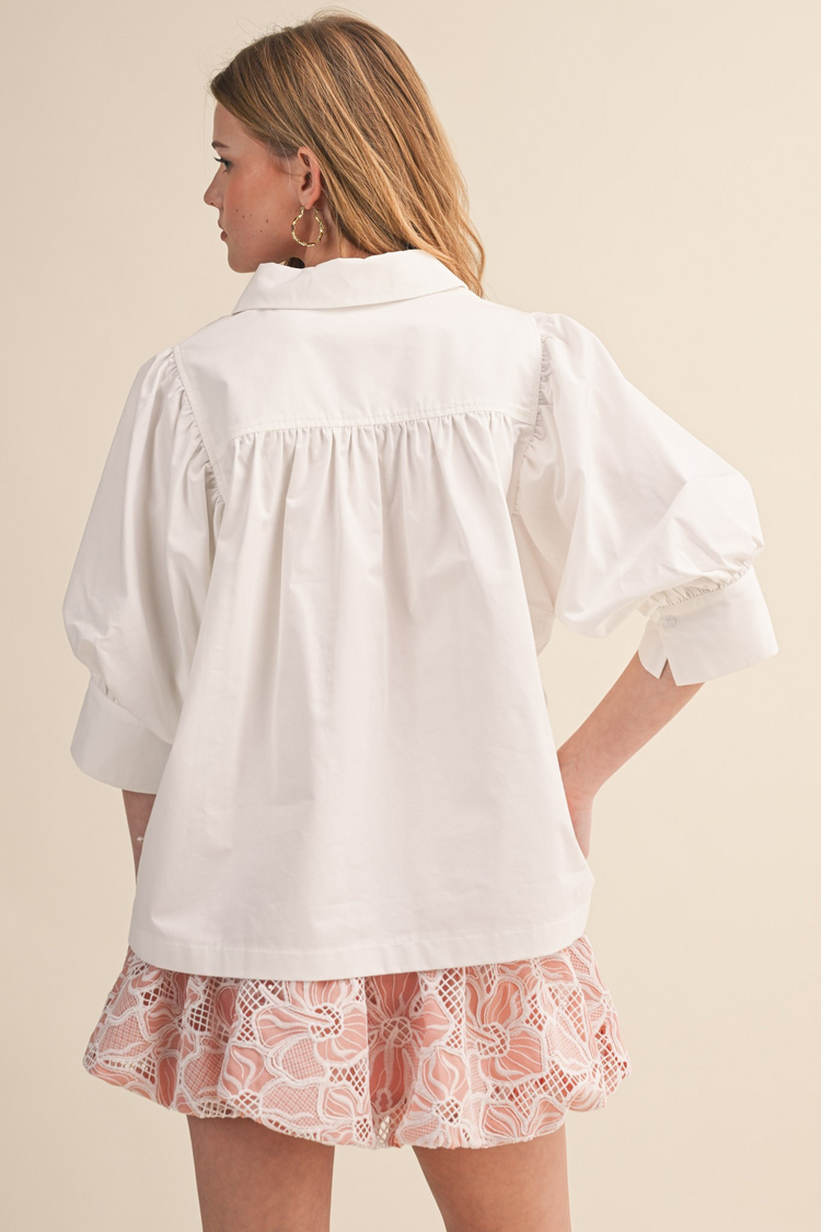 Back view of a woman wearing a white Krisha puff sleeve button down top with a pleated back yoke.