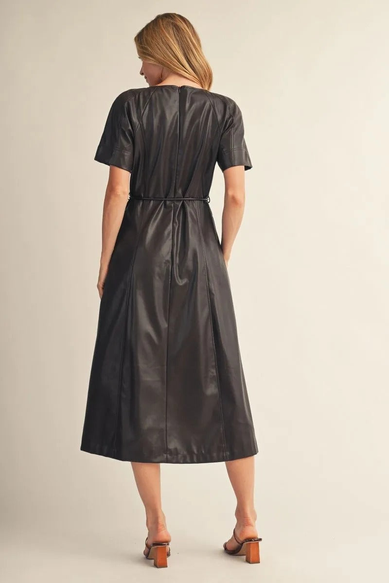 Back view of a woman wearing the Allison black faux leather midi dress with short sleeves.