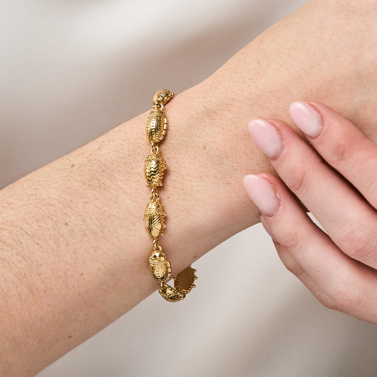 Gold Scarab Petite Linear Link Bracelet on a person's wrist with detailed beetle-shaped links.
