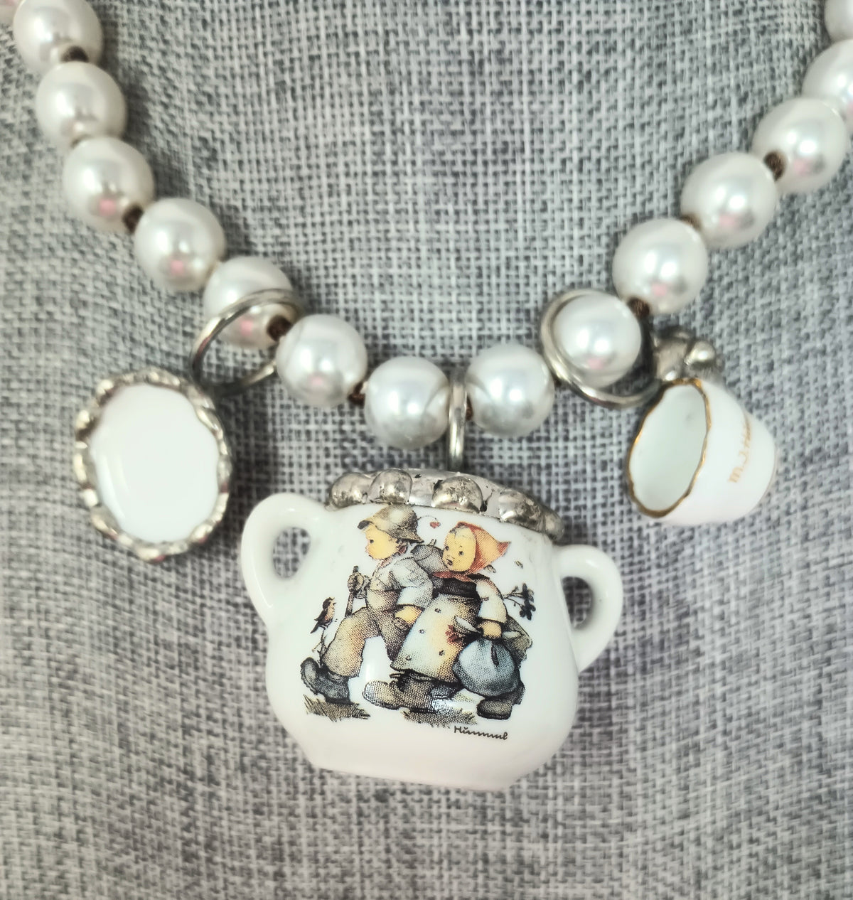 Porcelain teapot charm necklace featuring M.I. Hummel artwork on a silver chain