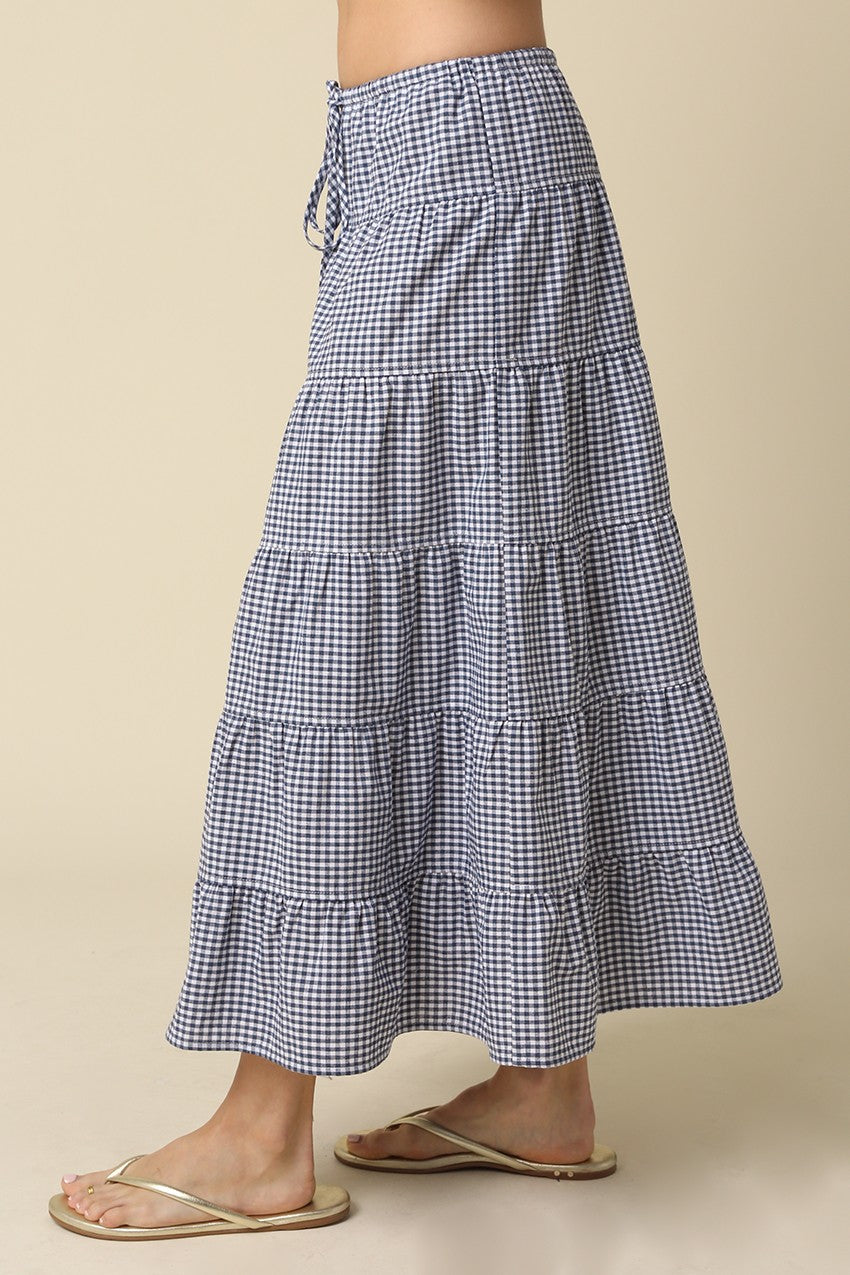 Side view of a blue and white gingham tiered maxi skirt with a drawstring waist.