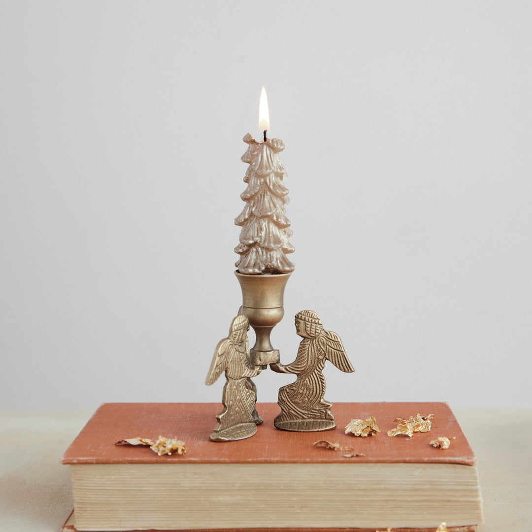 Gold finish metal taper holder featuring two kneeling angels supporting a lit tree-shaped candle.