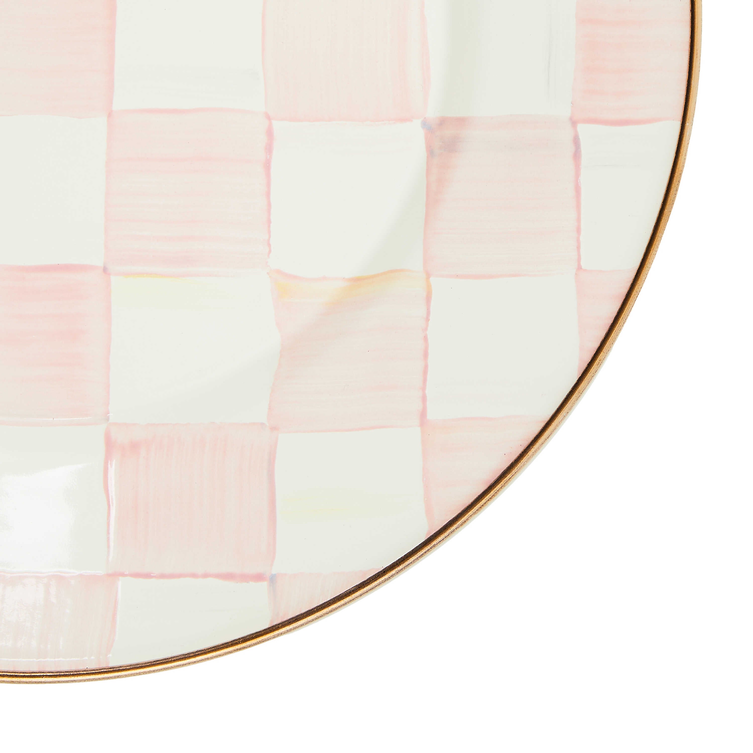 Close-up of a hand-painted pink and white checkered enamel dinner plate with a bronzed steel rim.