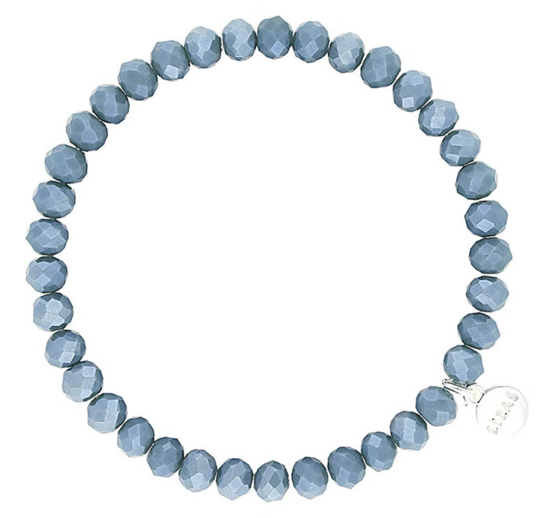 Lizas Quadro Big crystal stretch bracelet with faceted dusty blue beads and a silver logo charm.