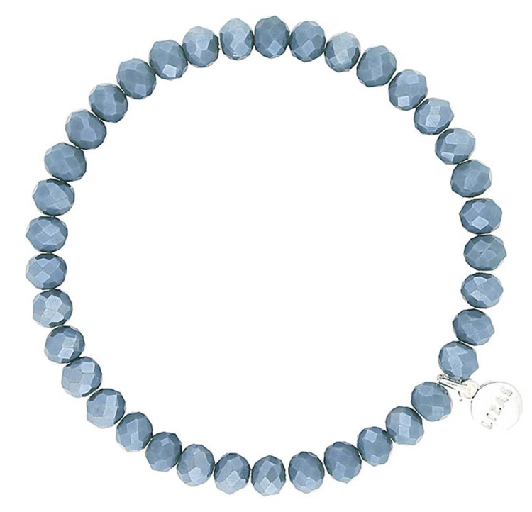 Lizas Quadro Big crystal stretch bracelet with faceted dusty blue beads and a silver logo charm.