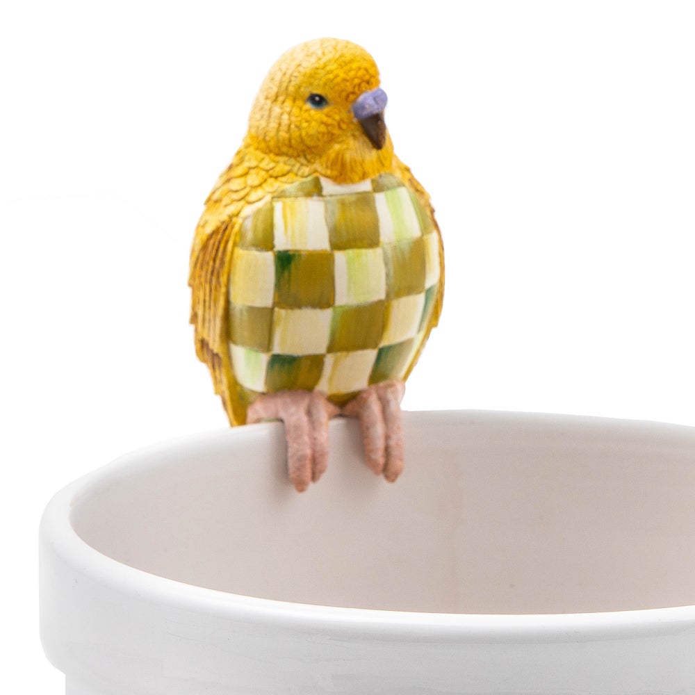 Yellow and chartreuse checkered parakeet resin pot climber perched on the edge of a white pot.