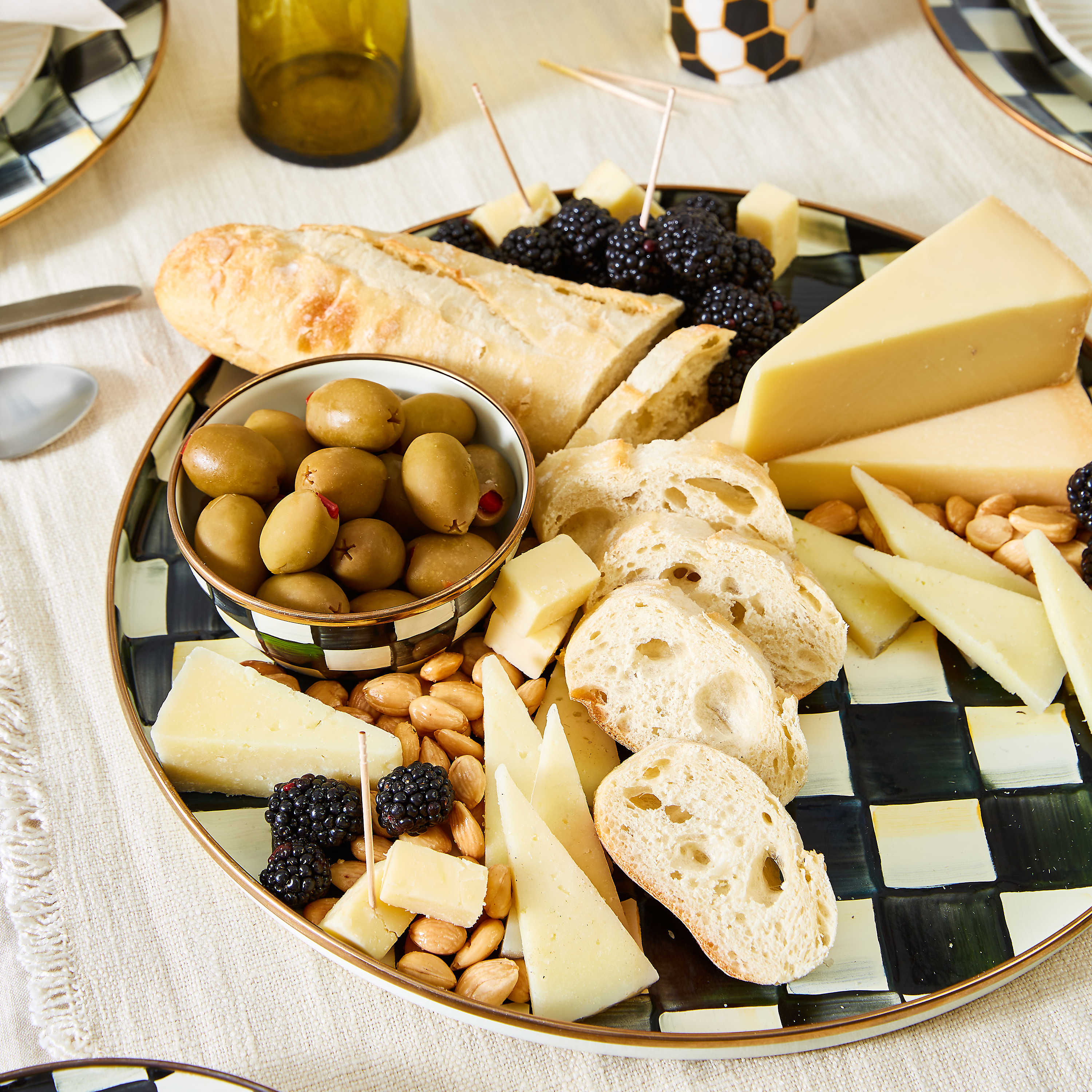 Courtly Check Enamel Pinch Bowl filled with olives on a charcuterie platter with bread and cheese.