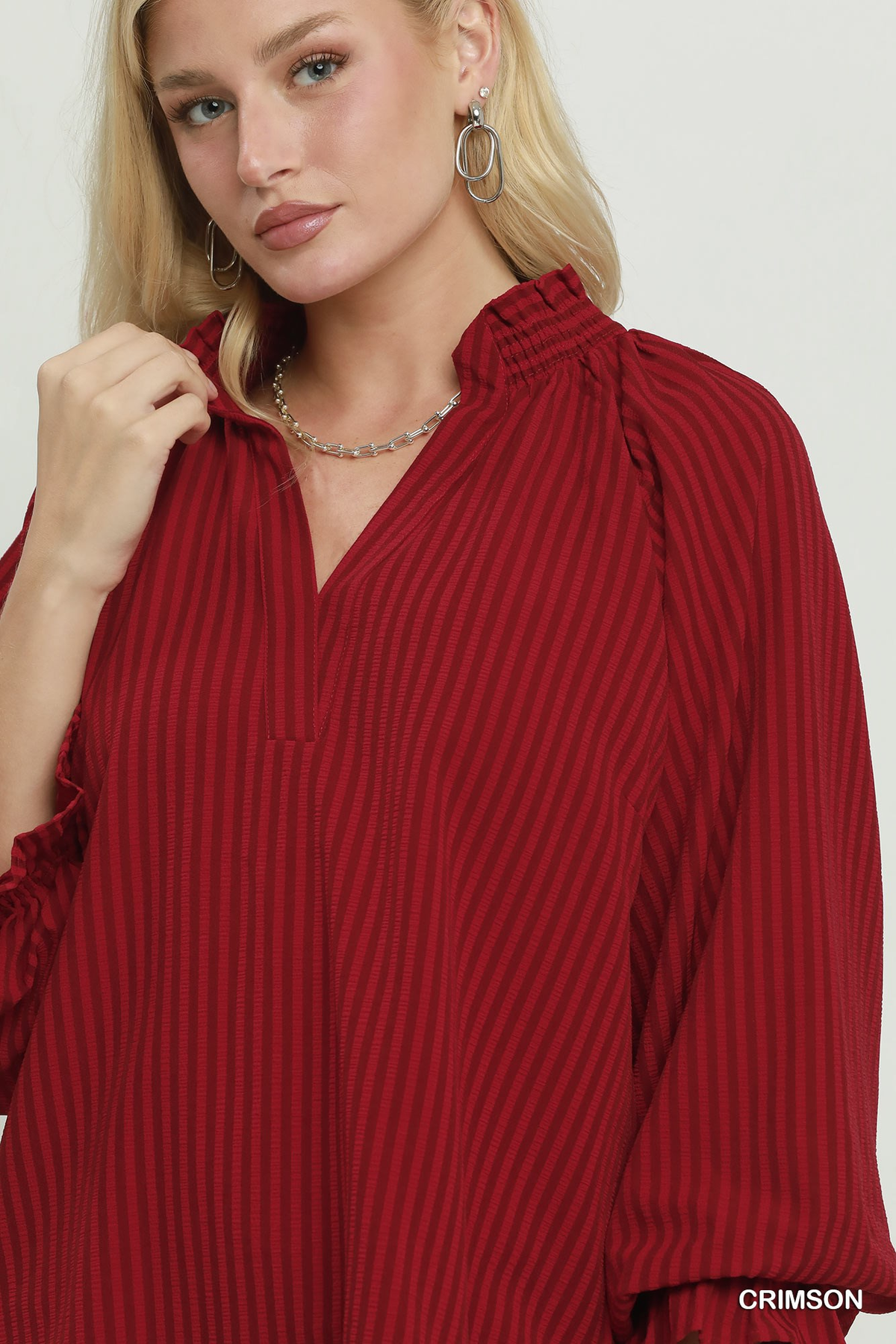 Close-up of a woman wearing the crimson Emma Stripe Split Neck Blouse with a ruffled collar.