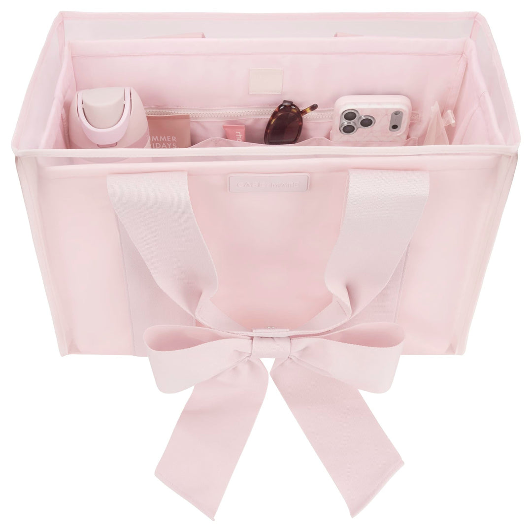 Pink structured tote organizer with compartments holding a water bottle, phone, and sunglasses.