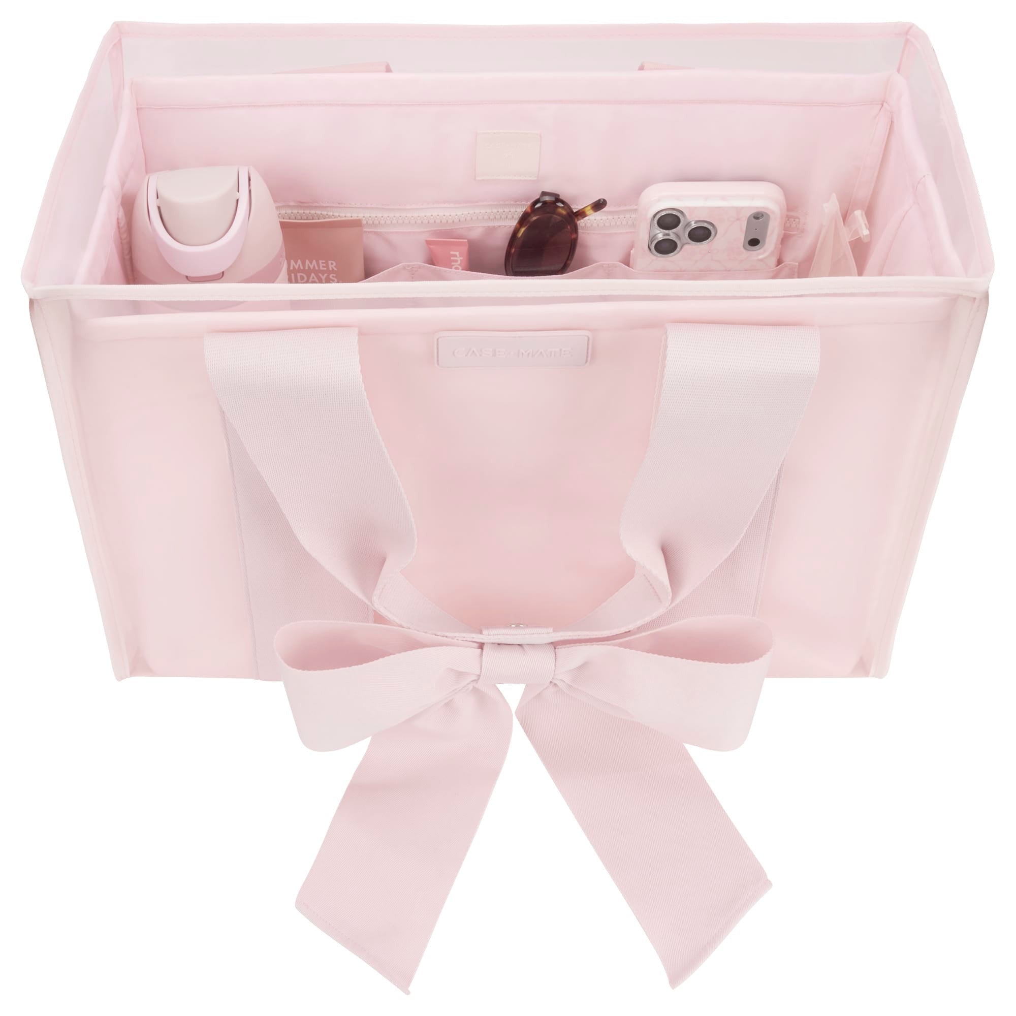 Pink structured tote organizer with compartments holding a water bottle, phone, and sunglasses.