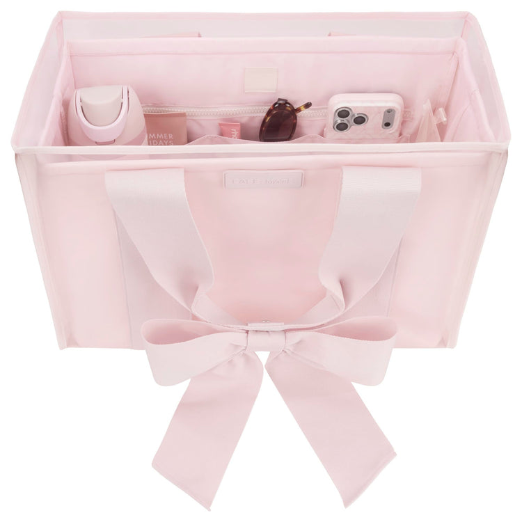 Pink structured tote organizer with compartments holding a water bottle, phone, and sunglasses.