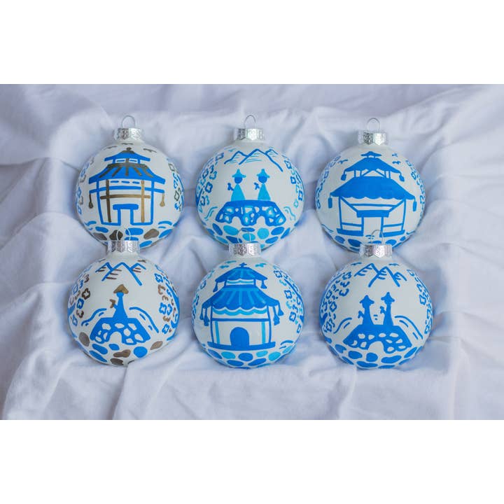 Hand-painted ceramic ornament featuring a pagoda scene with red roof tiles against a white background.