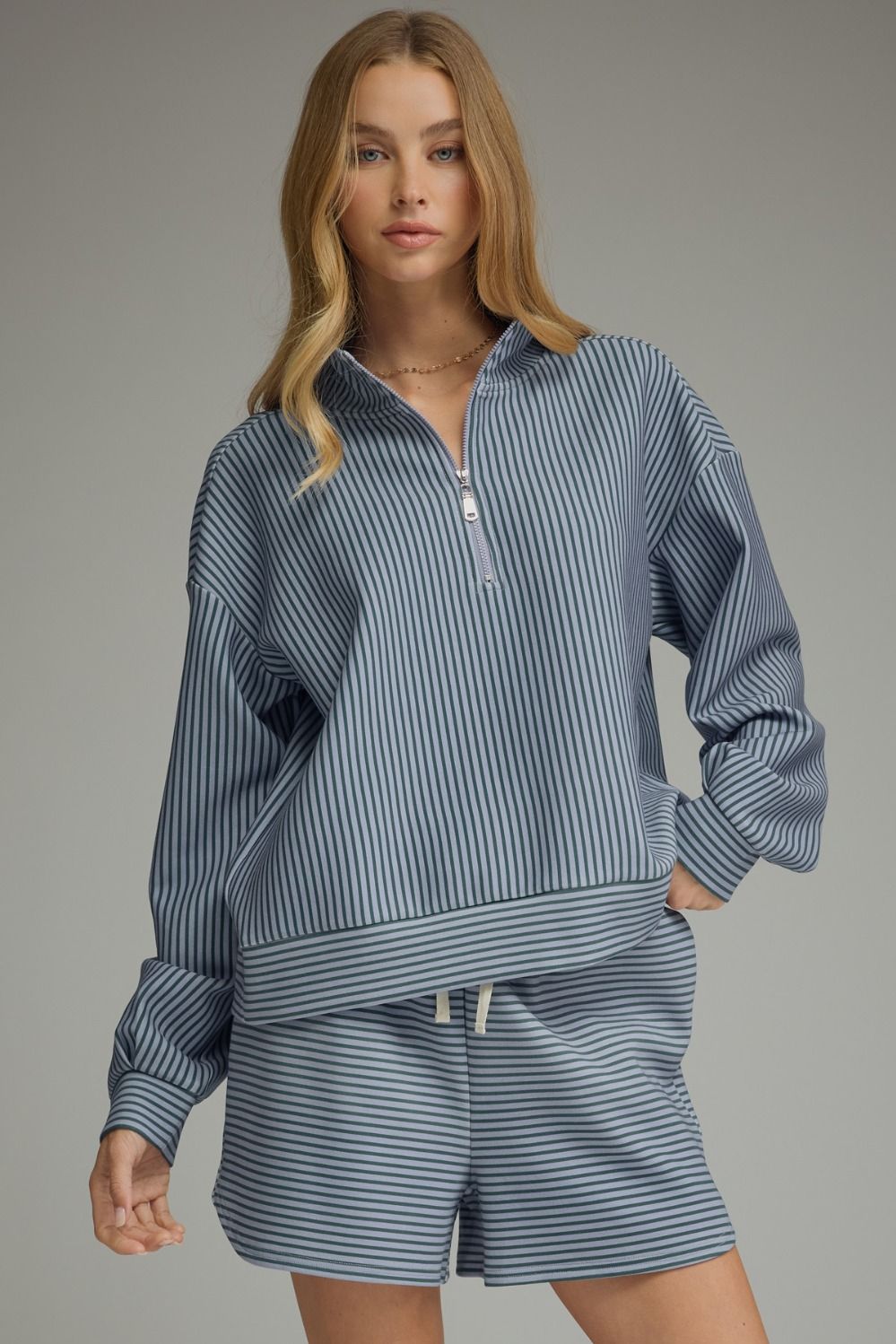 Woman wearing the Melissa blue and white stripe long sleeve knit top with a quarter zip front.