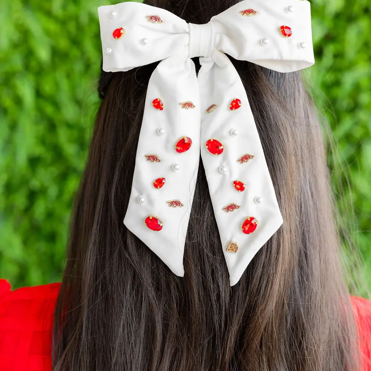 White bow barrette with University of Arkansas gold charms, red crystals, and white pearls.