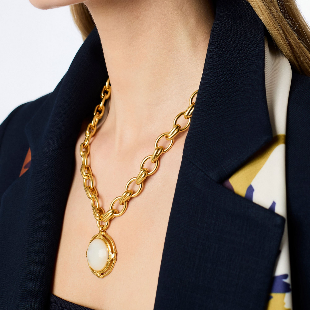Close-up of a woman wearing the gold Essex Statement Necklace with a large white stone pendant.